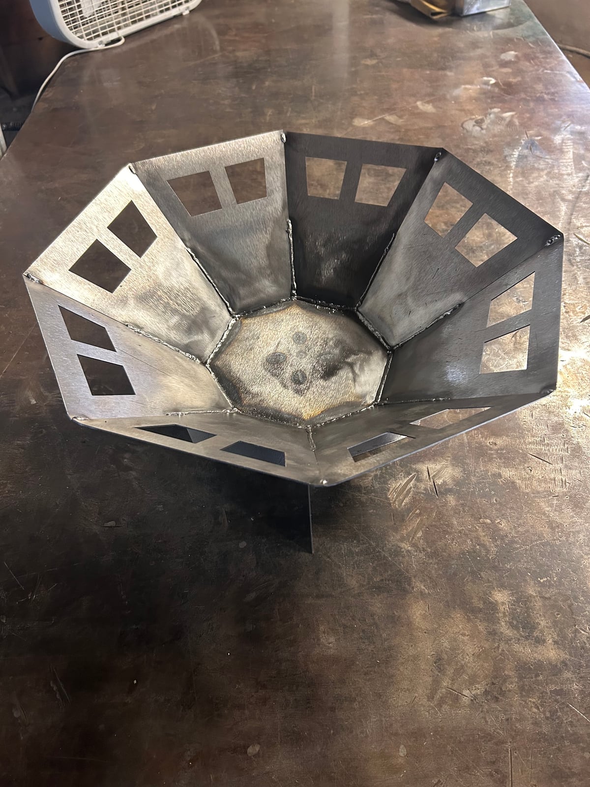 A faceted steel backyard fire pit with geometric cutouts